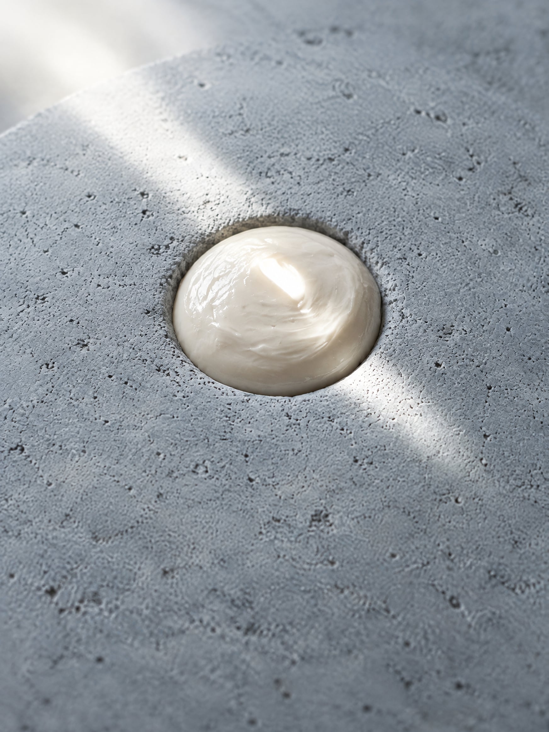 A milky-white paste filling a hollow in a gray stone is hardened with light.